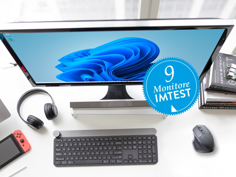 Weißer Monitor an weißem Schreibtisch schräg von oben zeigt Windows 11 Hintergrund