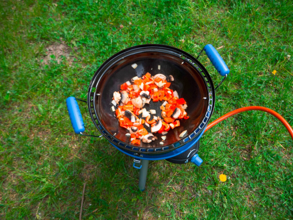 Mobiler Gasgrill von oben mit Gemüse in Wok