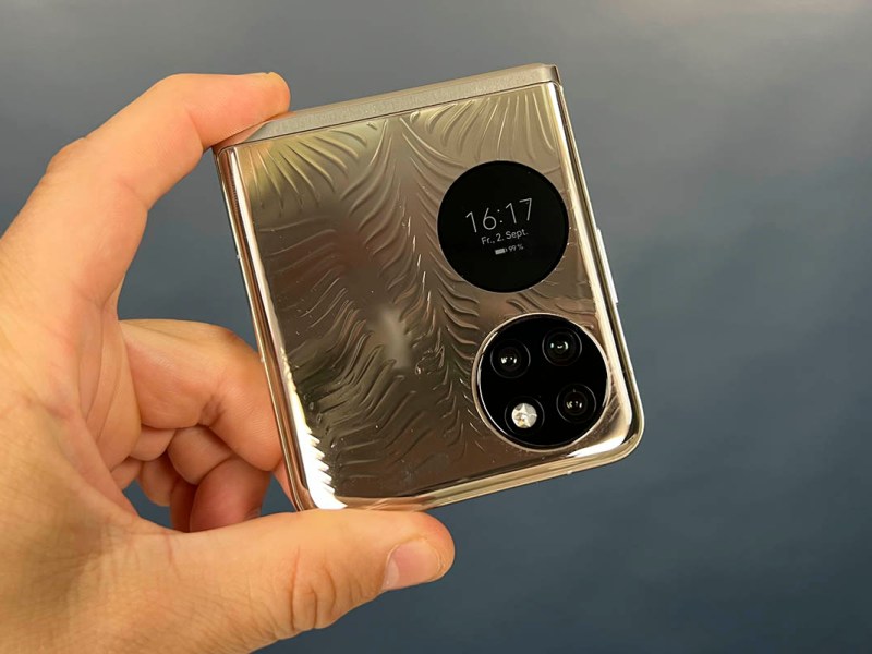 Huawei P50 Pocket zusammengeklappt zwischen zwei Fingern hochgehalten
