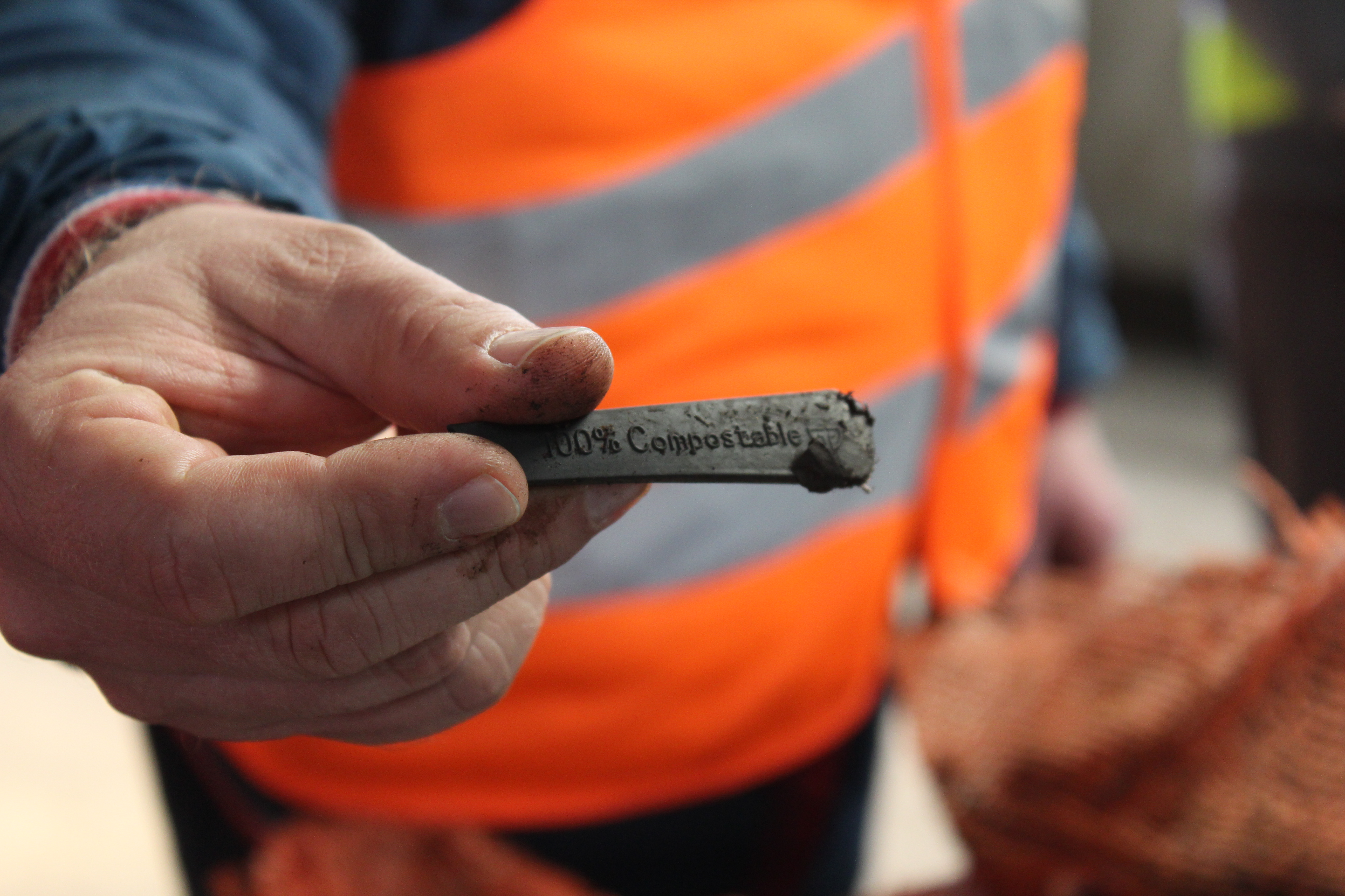 Ein Löffelstiel mit der Aufschrift "100 % Compostable" wird ins Bild gehalten.
