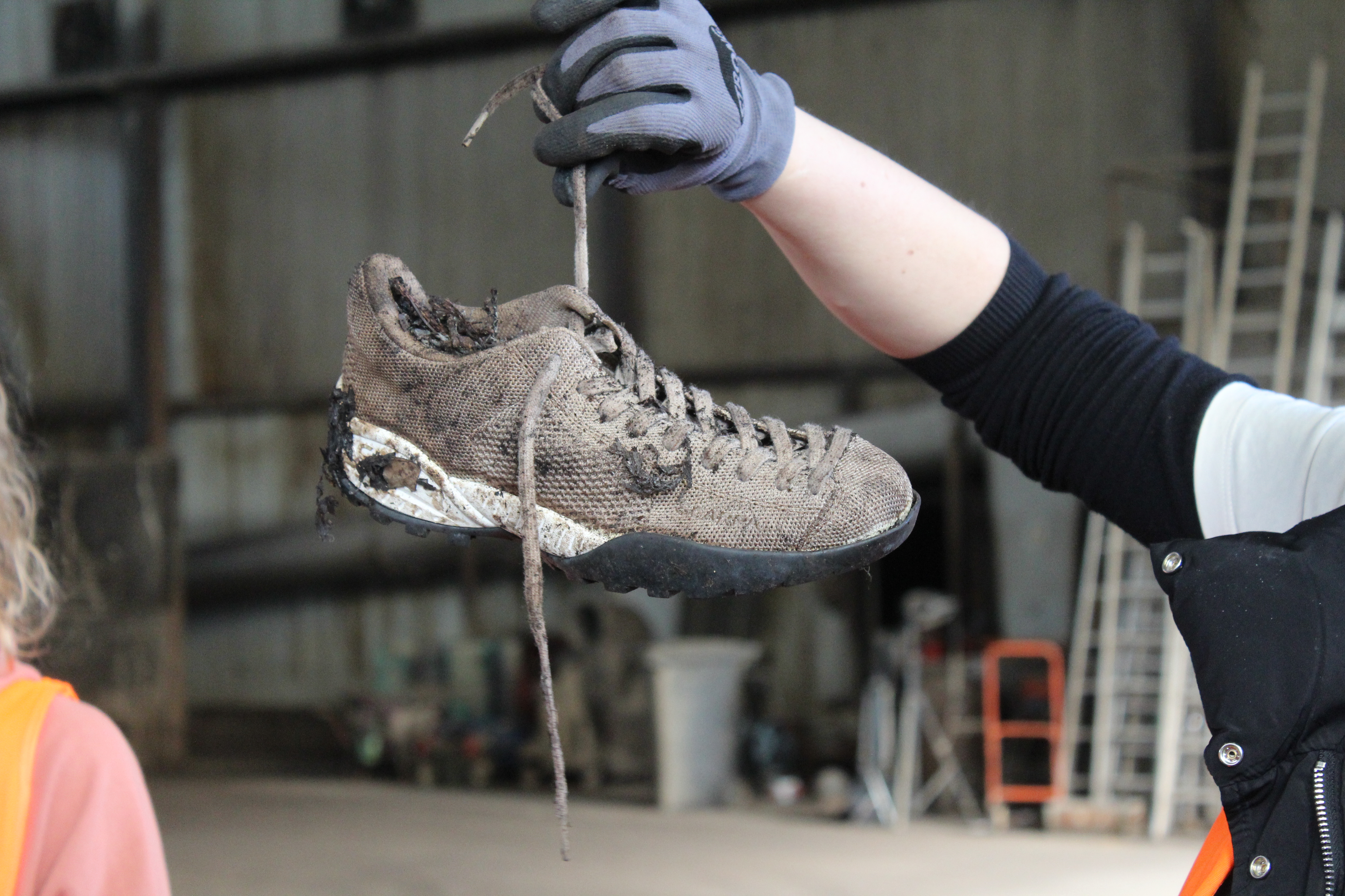 Ein Turnschuh wird an einem Schnürsenkel gehalten.
