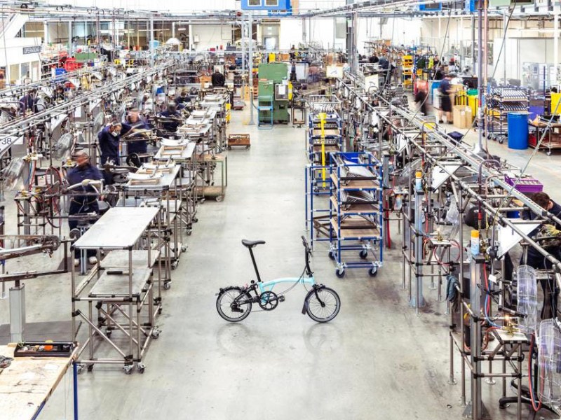 E-Faöt-Bike von Brompton steht in einer Fabrik vor Regalen.