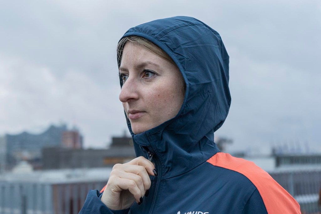 Detailbild Fau mit Sofshell-Jacke steht mit übergezogener Kapuze im Freien.