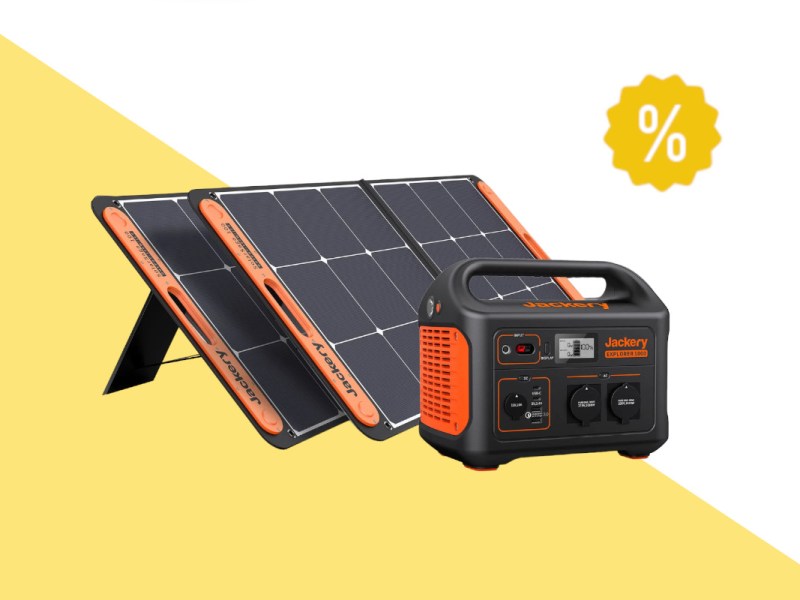Schwarz orangene Jackery Powerstation vor zwei hintereinander aufgestellten Solarpanels auf weiß gelben Hintergrund mit gelben Prozentzeichen rechts oben