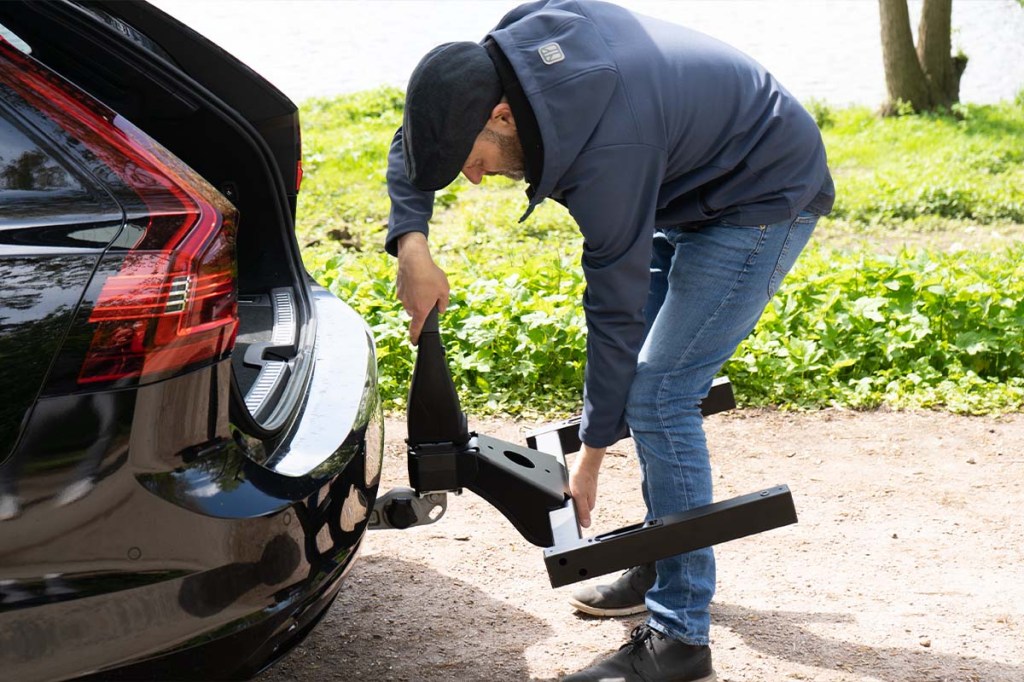 Mann bringt Heckboxenhalterung an Auto an