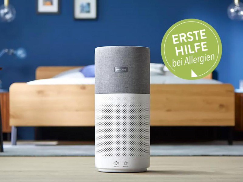 Ein Luftreiniger von Philips aufdem Boden vor einem Bett stehend.