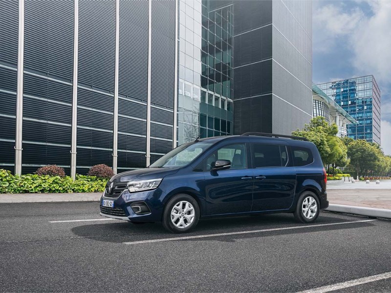 Renault Grand Kangoo E-Tech Electric auf einer Straße, im Hintergrund Bürogebäude