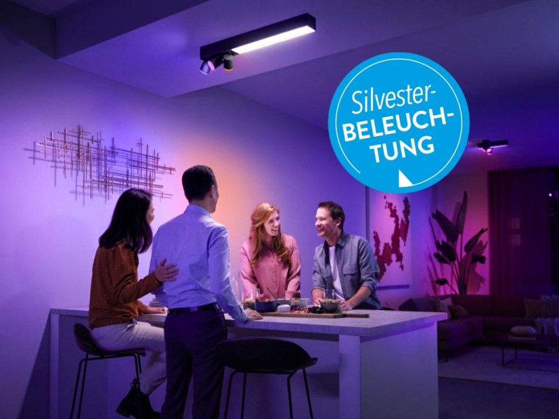Personengruppe um einen Tisch mit bunter Beleuchtung.