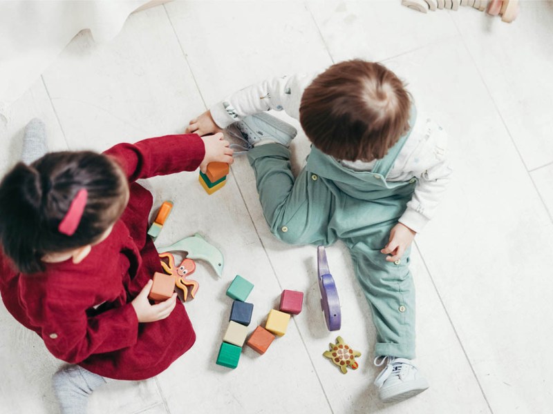 Zwei Kinder spielen mit bunten Bauklötzen