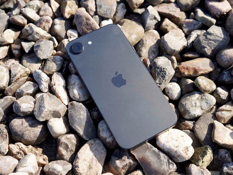 Das Apple iPhone 16e liegt auf Kies in der Sonne.